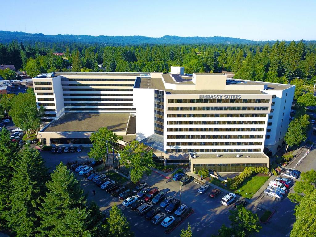 un edificio de oficinas con coches estacionados en un estacionamiento en Embassy Suites by Hilton Portland Washington Square en Tigard