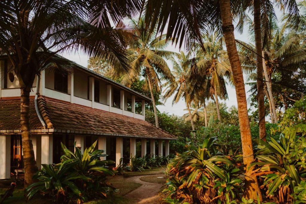 a building with palm trees in front of it at Amuura Beach Villa in Beruwala