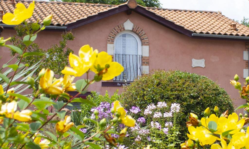 una casa con flores amarillas delante de ella en Chambres d'Hôtes Au Grillon Dort, en Moustey