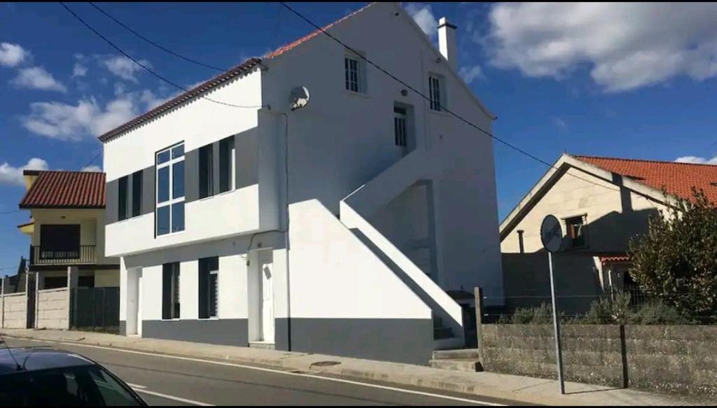 un edificio blanco al lado de una calle en Casa dala, en aguiño, en Ribeira