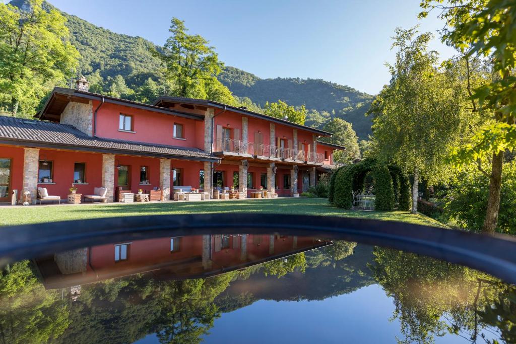 un bâtiment rouge avec une réflexion dans l'eau dans l'établissement Agriturismo Scuderia della Valle, à Valsecca