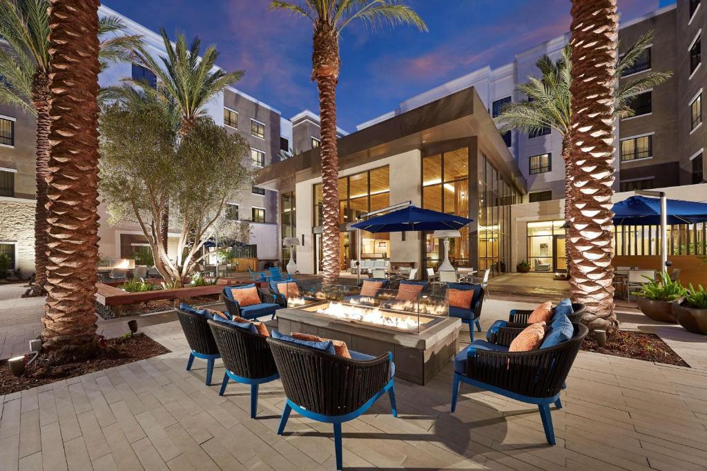 um pátio com cadeiras, mesas e palmeiras em Homewood Suites by Hilton San Diego Hotel Circle/SeaWorld Area em San Diego