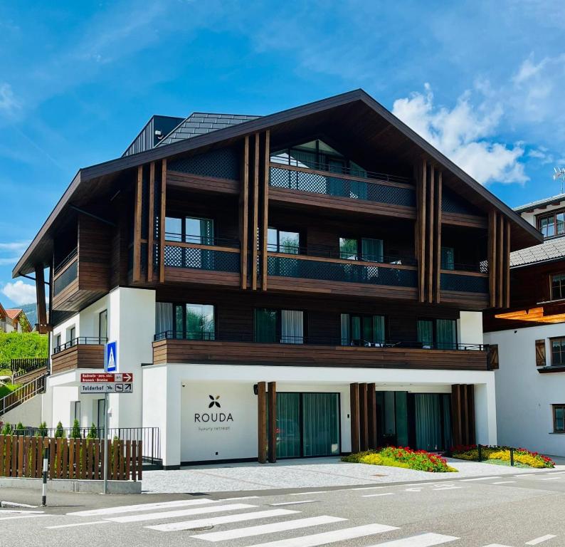 un immeuble d'appartements avec un toit en bois dans l'établissement ROUDA luxury retreat am Kronplatz, à Valdaora