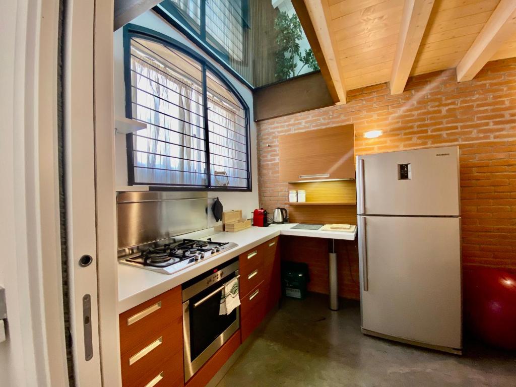 een keuken met een witte koelkast en een fornuis bij Luxury industrial apt vicino al centro con garage in Brescia