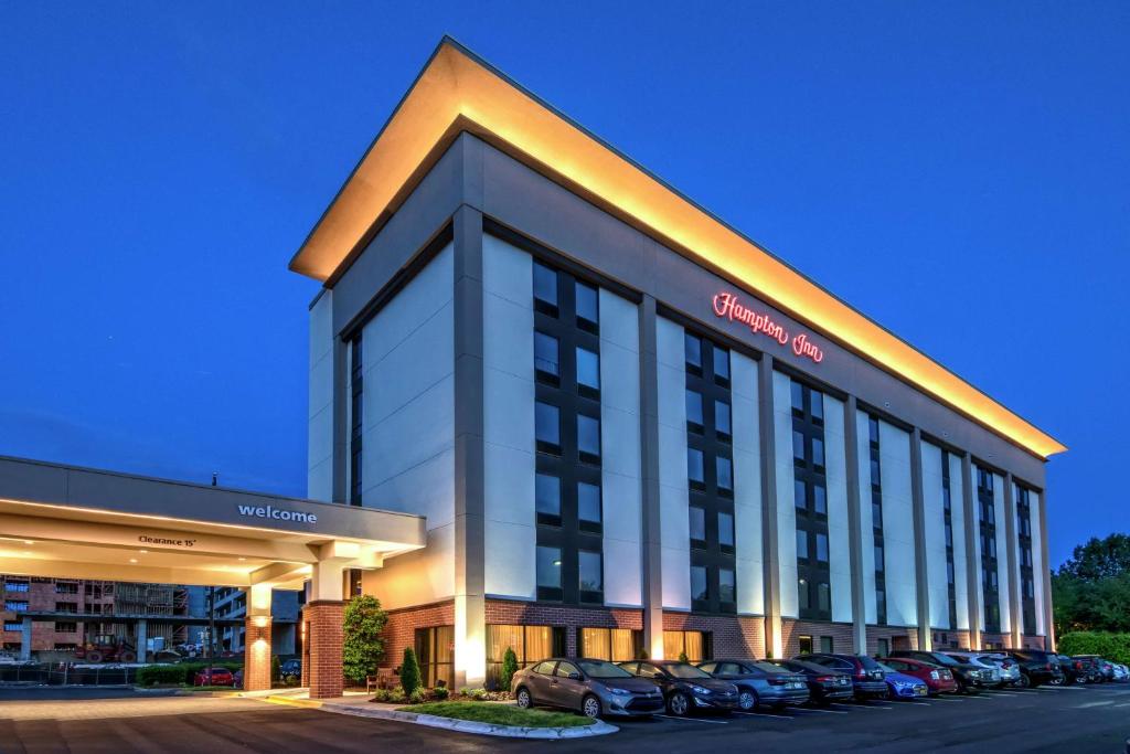 a large building with cars parked in a parking lot at Hampton Inn Charlotte University Place in Charlotte