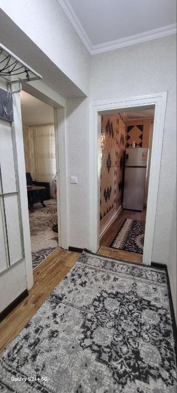 an empty living room with a kitchen and a refrigerator at Cozy apartment in Tashkent