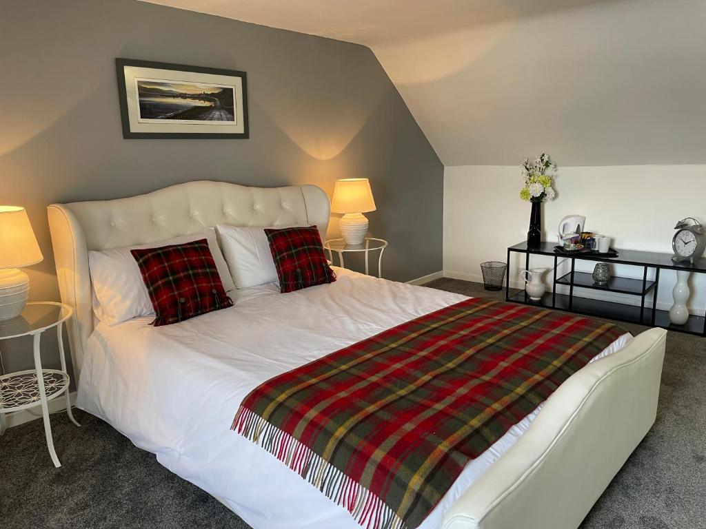 a bedroom with a white bed with red and green pillows at The Old Rectory in Inveraray