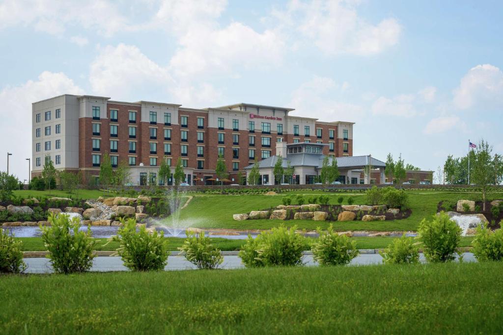 a building with a fountain in the middle of a park at Hilton Garden Inn Exton-West Chester in Exton