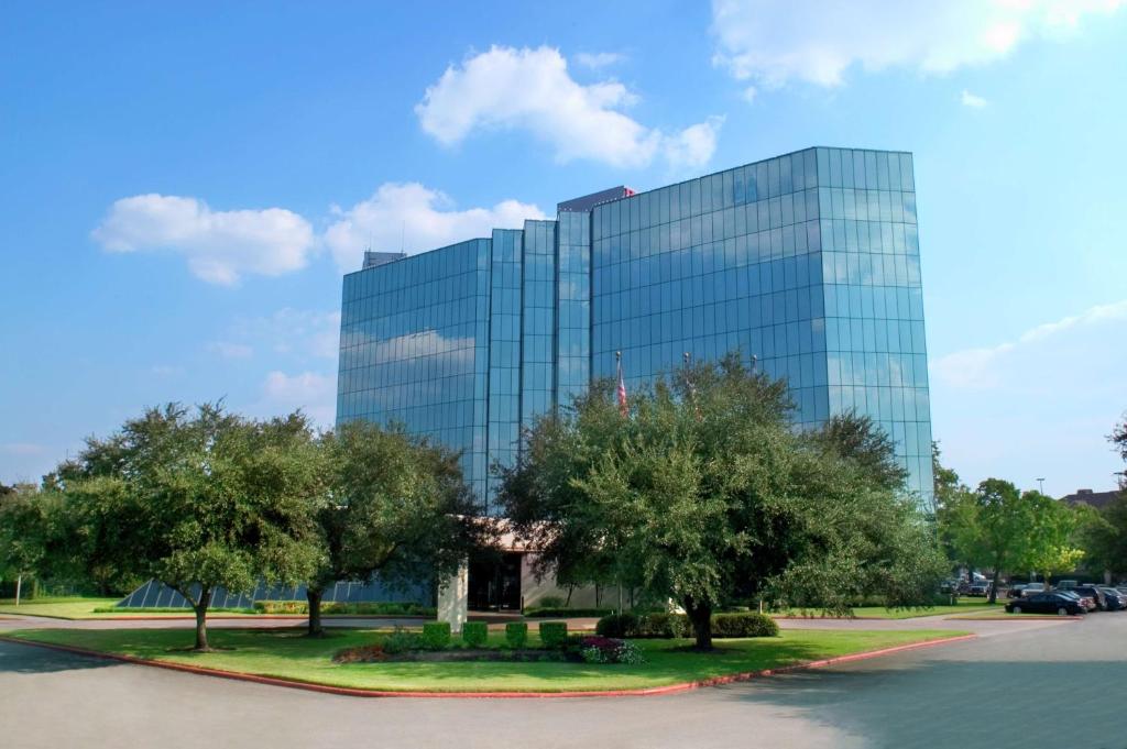a glass building with trees in front of it at Hilton Houston Westchase in Houston