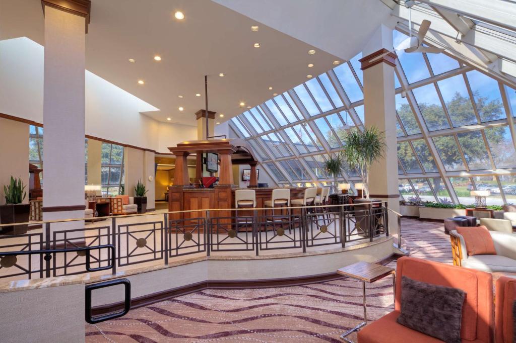 a lobby with a glass ceiling and tables and chairs at Hilton Houston Westchase in Houston