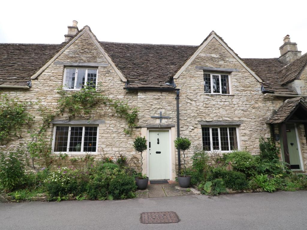 科姆堡的住宿－Castle Combe Cottage，一座带白色门的老石屋