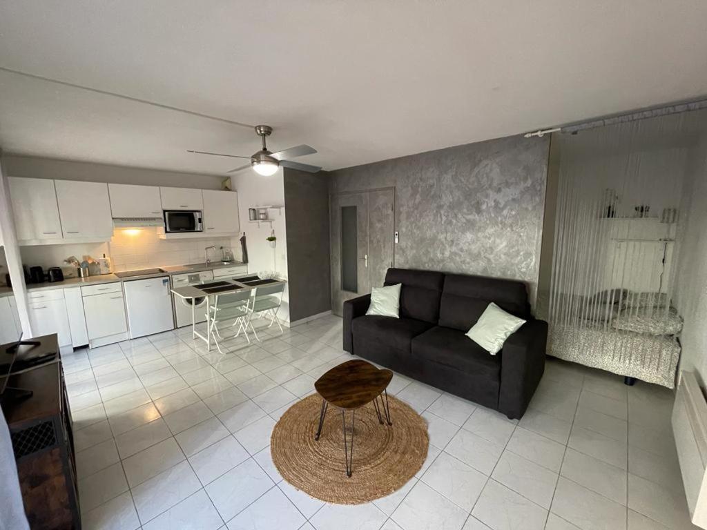un salon avec un canapé noir et une cuisine dans l'établissement Appartement proche mer, à Cannes
