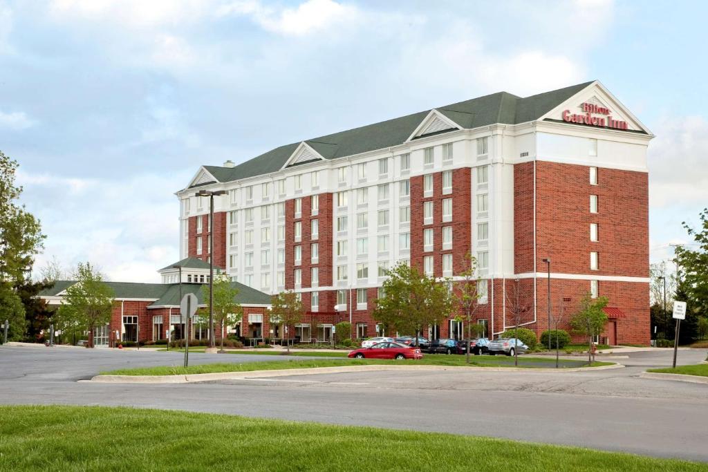 a large red and white building on a street at Hilton Garden Inn Hoffman Estates in Hoffman Estates
