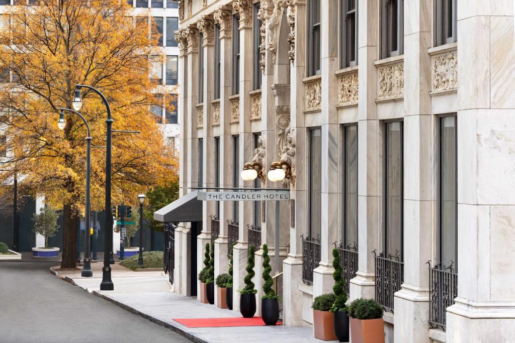 a building on a street with potted plants on the sidewalk at The Candler Hotel Atlanta, Curio Collection by Hilton in Atlanta