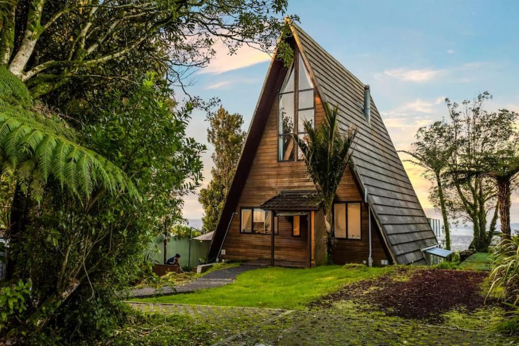 a small wooden house with a gambrel roof at Nature's Nook with Spa, Deck and Views in Piha