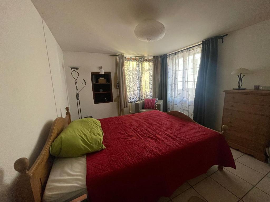 ein Schlafzimmer mit einem roten Bett mit einer roten Decke in der Unterkunft Chambre atypique in Saint-Blaise