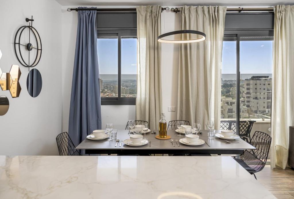 a dining room with a table and chairs and windows at Jerusalem Luxury Apartments by IB Properties in Jerusalem