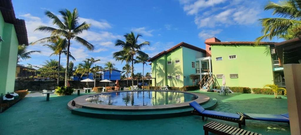 un complejo con piscina y palmeras en Condomínio Golden Dolphin Village, en Porto Seguro