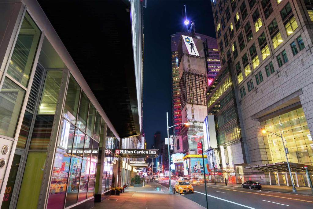 une rue de la ville la nuit avec des bâtiments et un taxi dans l'établissement Hilton Garden Inn New York - Times Square Central, à New York