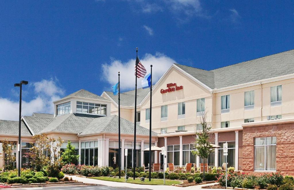 an exterior view of a hotel with an american flag at Hilton Garden Inn Norman in Norman
