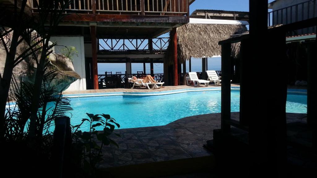 una piscina en un complejo con sillas y un edificio en La Delphina Bed and Breakfast Bar and Grill, en La Ceiba