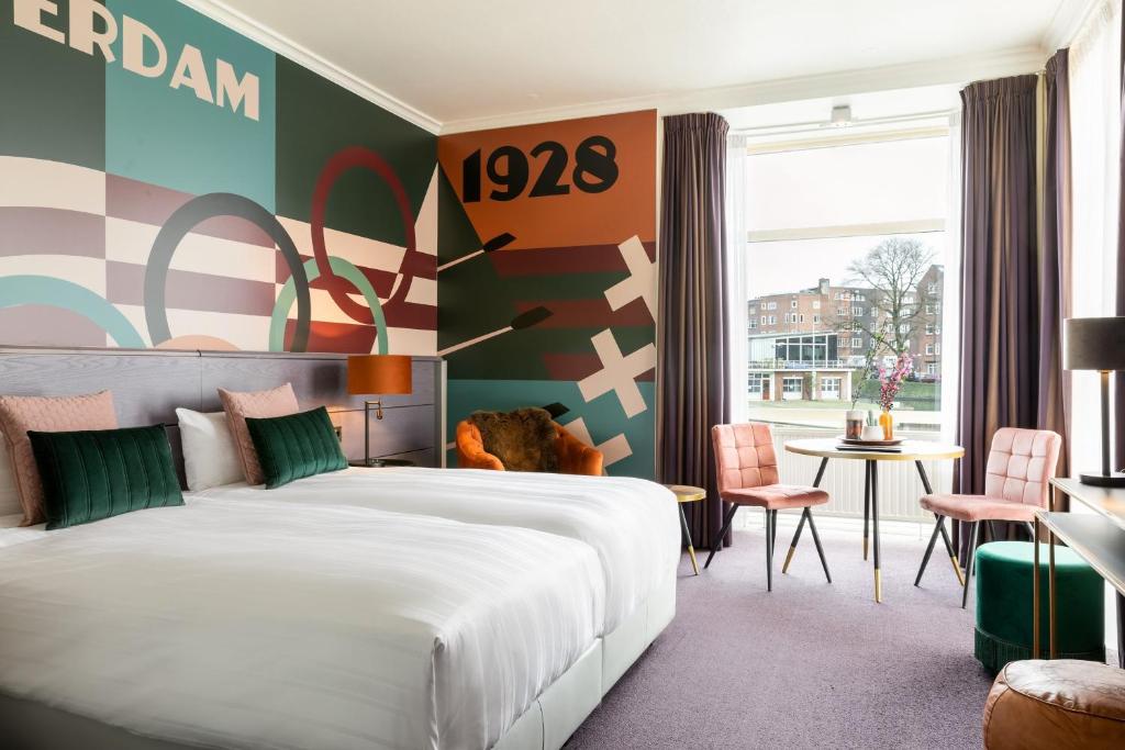 a hotel room with a bed and a table and chairs at Apollo Hotel Amsterdam, a Tribute Portfolio Hotel in Amsterdam