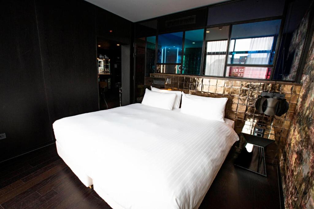 a large white bed in a room with windows at Apollo Hotel Amsterdam, a Tribute Portfolio Hotel in Amsterdam