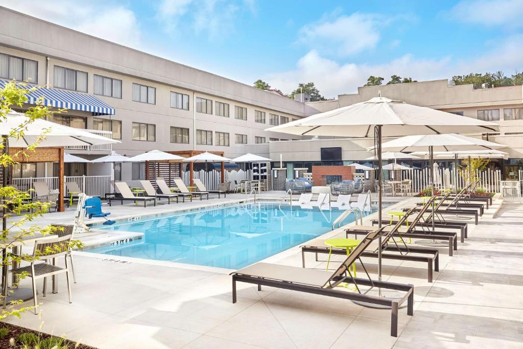 una piscina de hotel con tumbonas y sombrillas en DoubleTree Suites by Hilton Nashville Airport, en Nashville