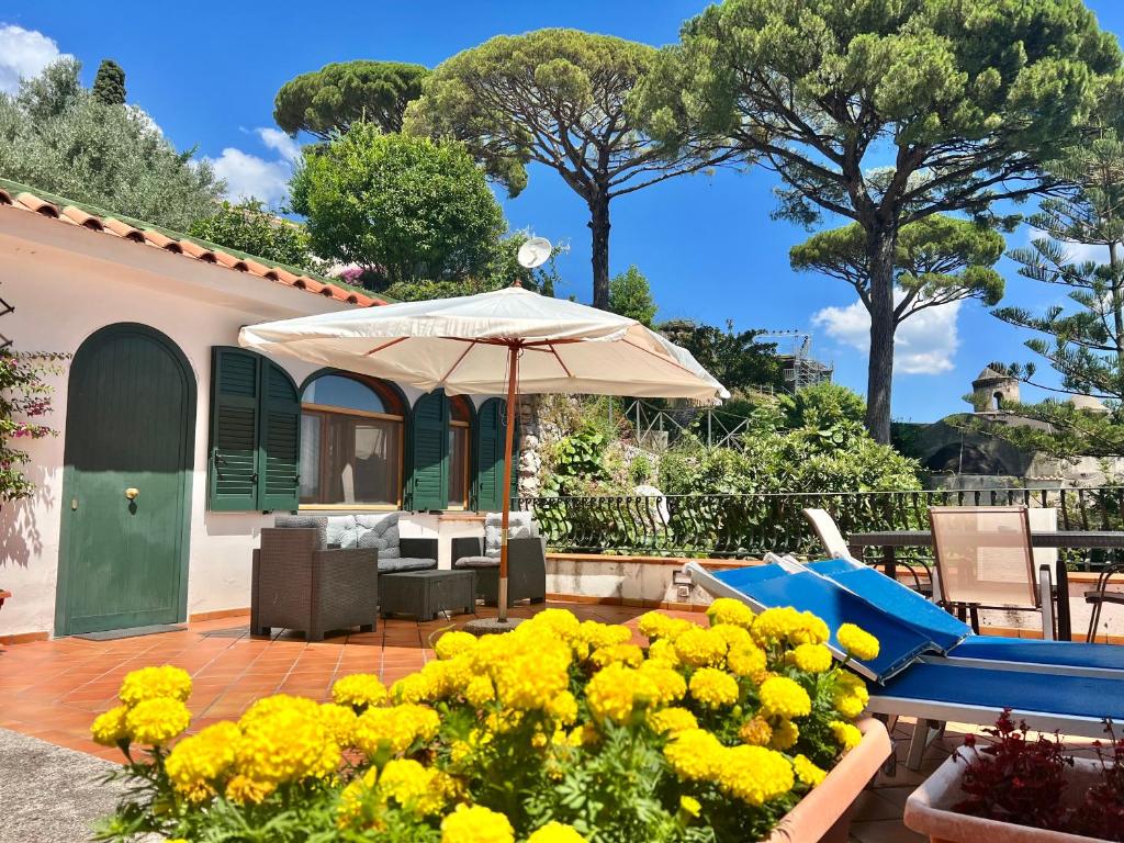 拉維羅的住宿－Casa Ravello，天井配有桌子、雨伞和黄色鲜花。