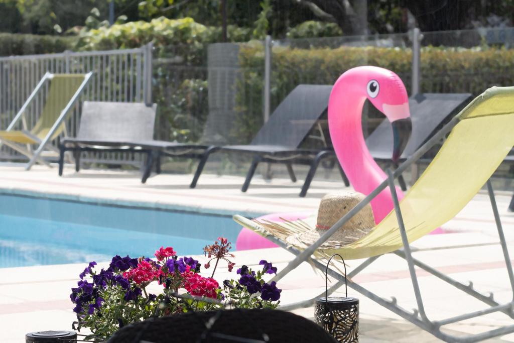 un fauteuil flamant rose et des fleurs à côté de la piscine dans l'établissement Novotel Evry Courcouronnes, à Courcouronnes
