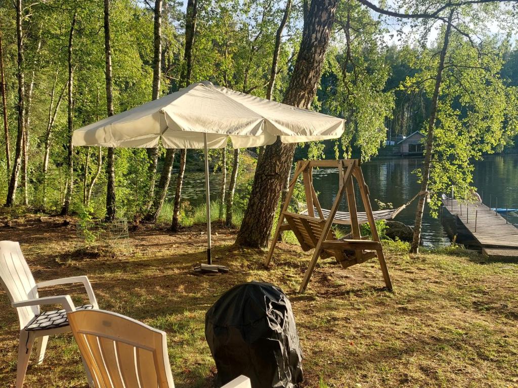 a tent and chairs and a hammock in a yard at Lakeside Hilda, rantamökki 