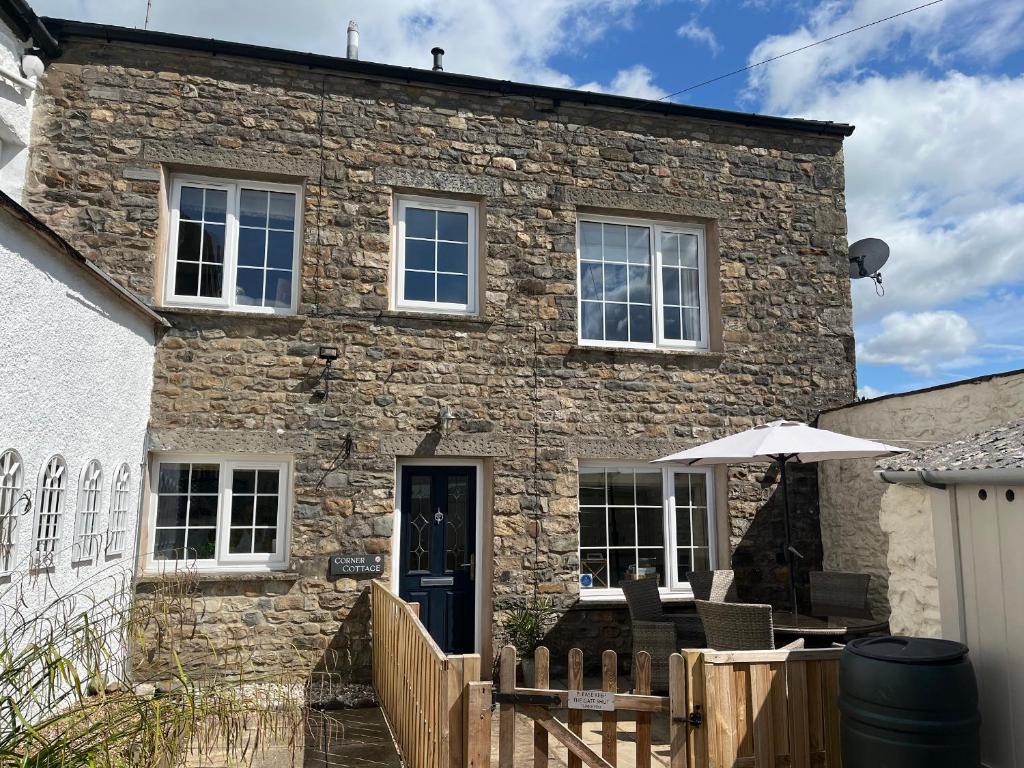 a stone house with an umbrella in front of it at Corner Cottage in Sedbergh