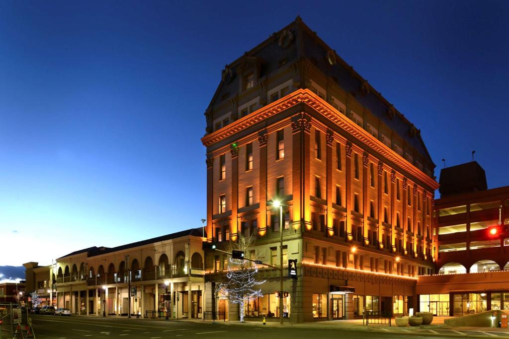Un grand bâtiment en briques est éclairé la nuit. dans l'établissement Hotel Maison Yakima Tapestry Collection by Hilton, à Yakima
