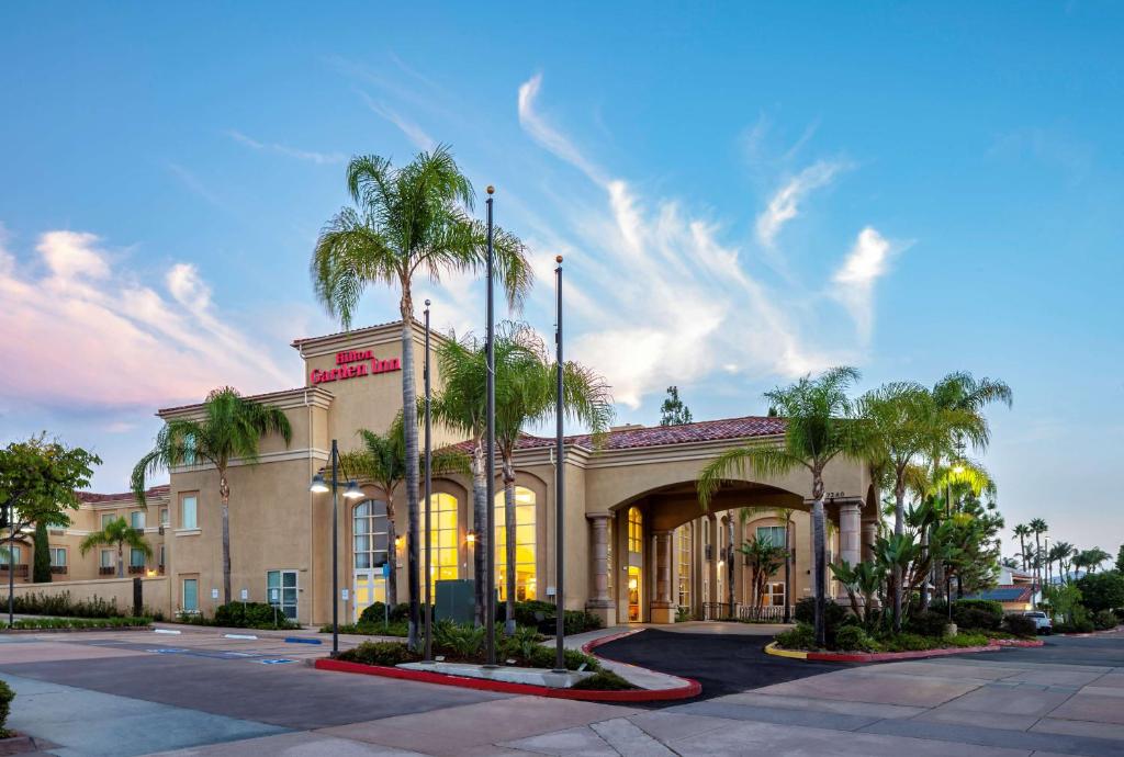 un hôtel avec des palmiers devant un bâtiment dans l'établissement Hilton Garden Inn San Diego/Rancho Bernardo, à Rancho Bernardo