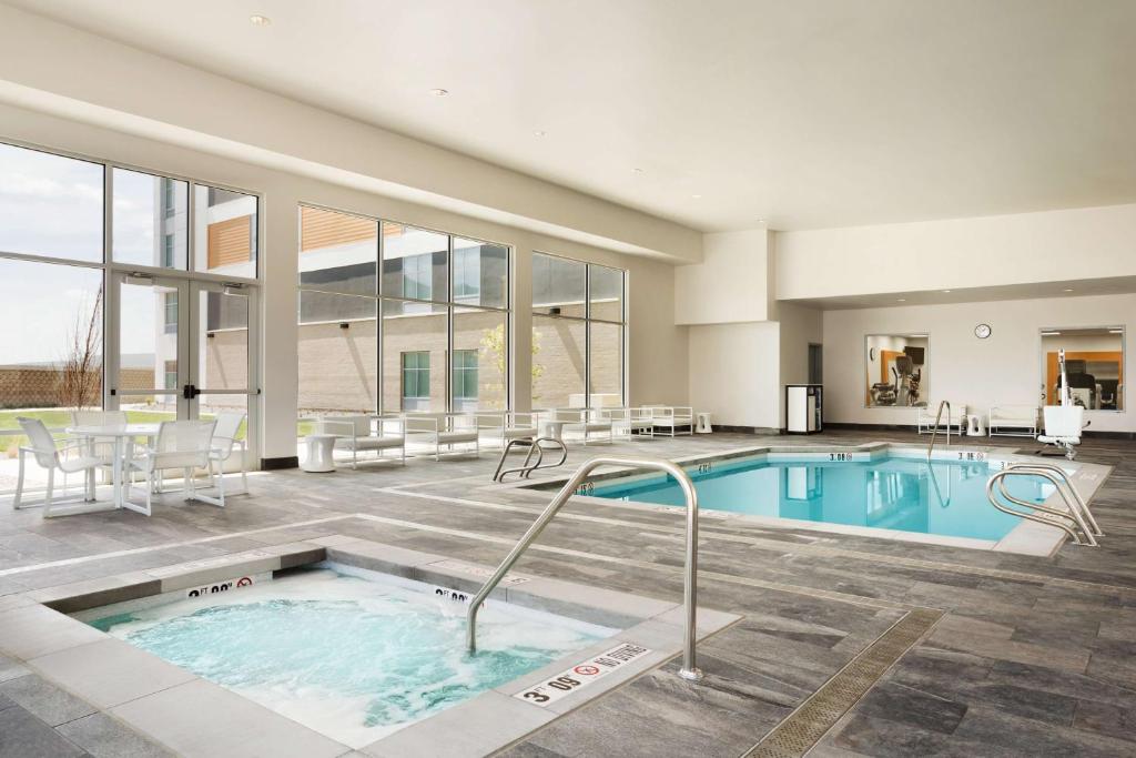 a pool in a building with a table and chairs at Homewood Suites By Hilton SLC/Draper in Draper