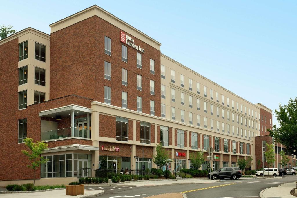 a large red brick building on a city street at Hilton Garden Inn Westchester Dobbs Ferry in Dobbs Ferry