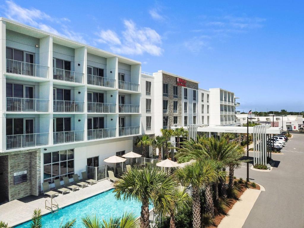 an aerial view of a hotel with a swimming pool and palm trees at Hilton Garden Inn Destin Miramar Beach, Fl in Destin