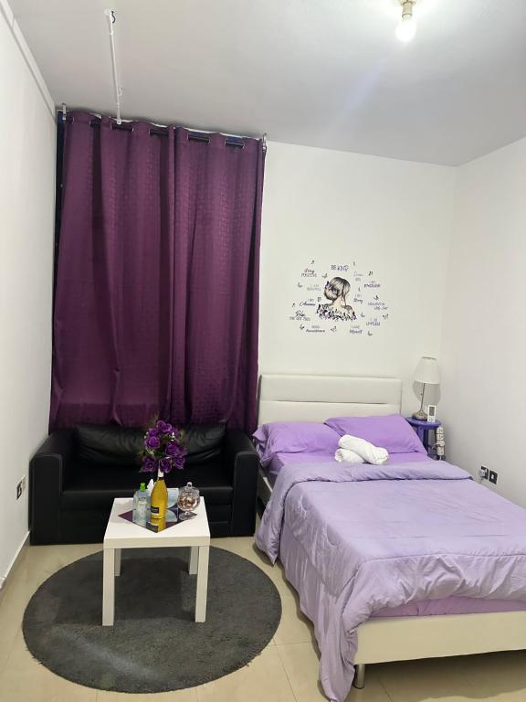 The Purple Place في أبوظبي: غرفة نوم بسريرين وطاولة مع شراشف أرجوانية