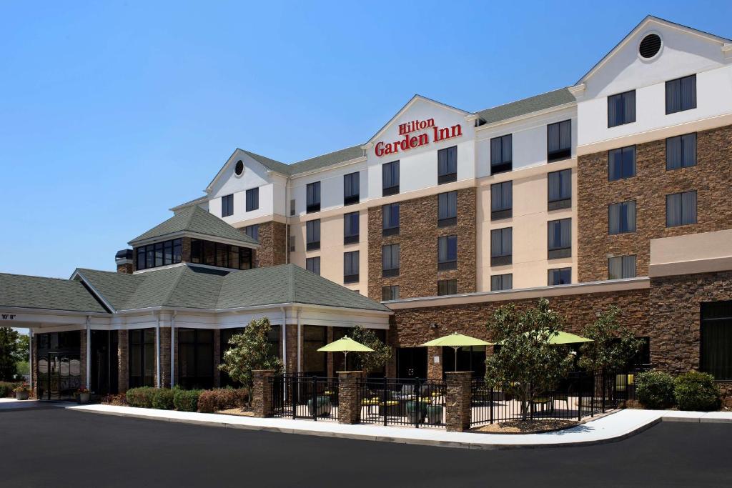 a hotel with tables and umbrellas in front of a building at Hilton Garden Inn Atlanta West/Lithia Springs in Lithia Springs