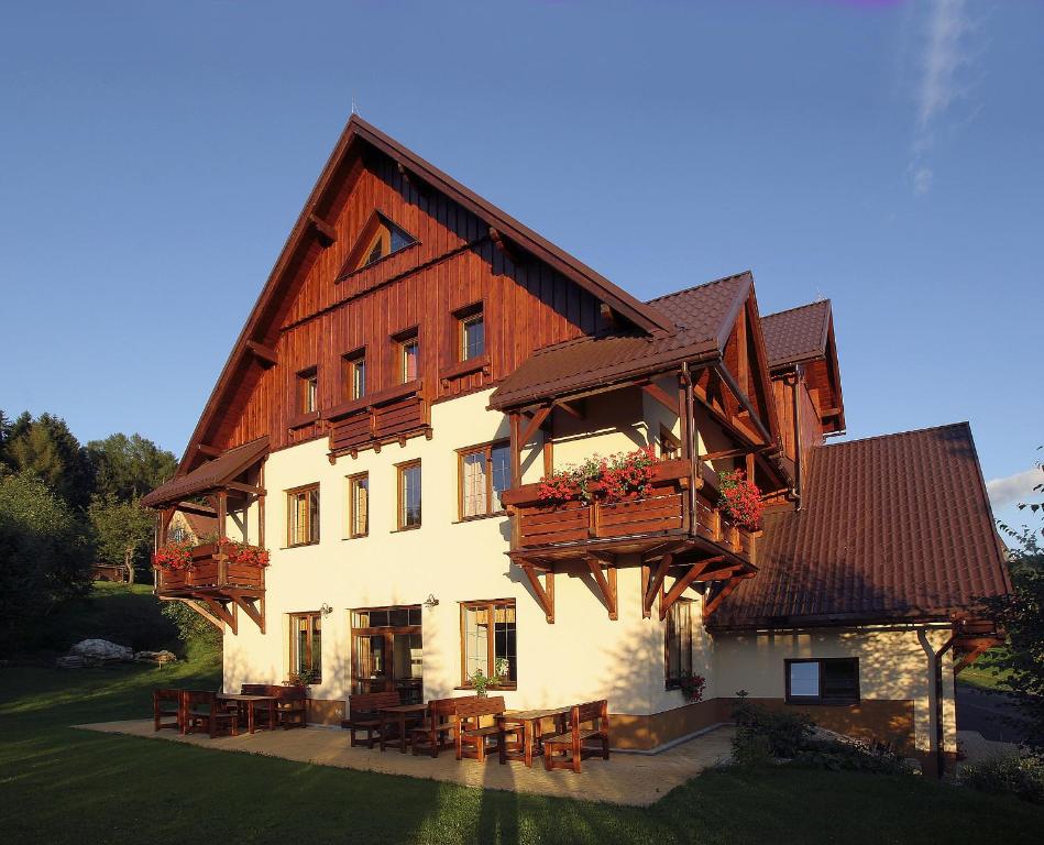 a large house with wooden balconies and tables on it at Penzion Bona in Rokytnice nad Jizerou