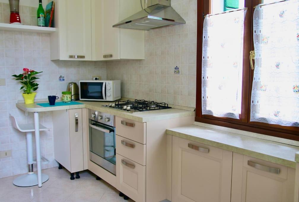 a kitchen with a stove and a microwave at Isola del Lido, Luminoso, immerso nel verde, per 5 in Venice-Lido