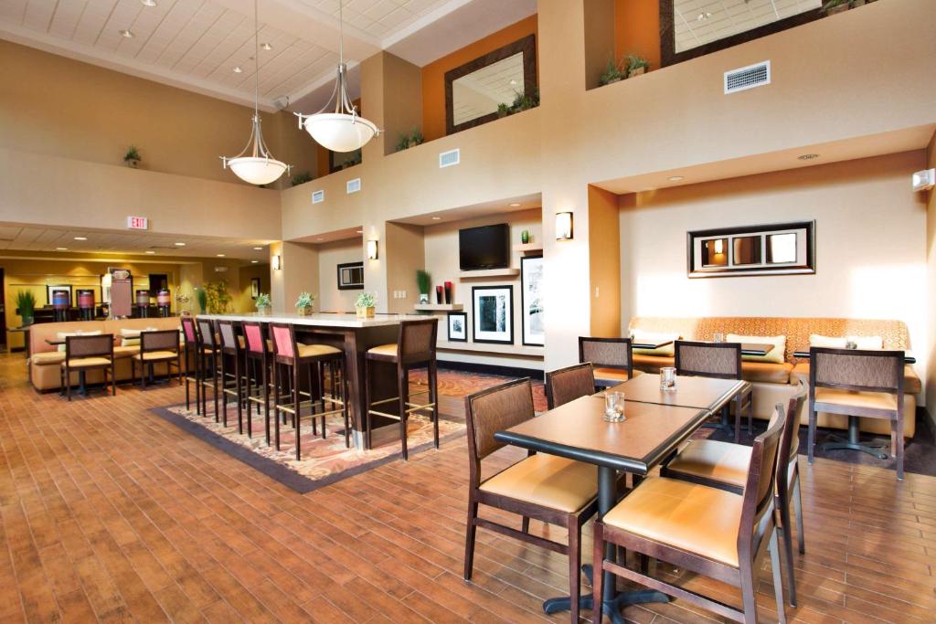 a restaurant with tables and chairs and a bar at Hampton Inn & Suites Laurel in Laurel