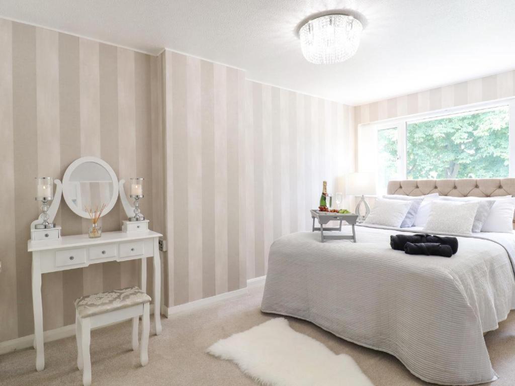 a white bedroom with a large bed and a mirror at Gorgeous 3 bed House In Bletchley Milton Keynes in Bletchley