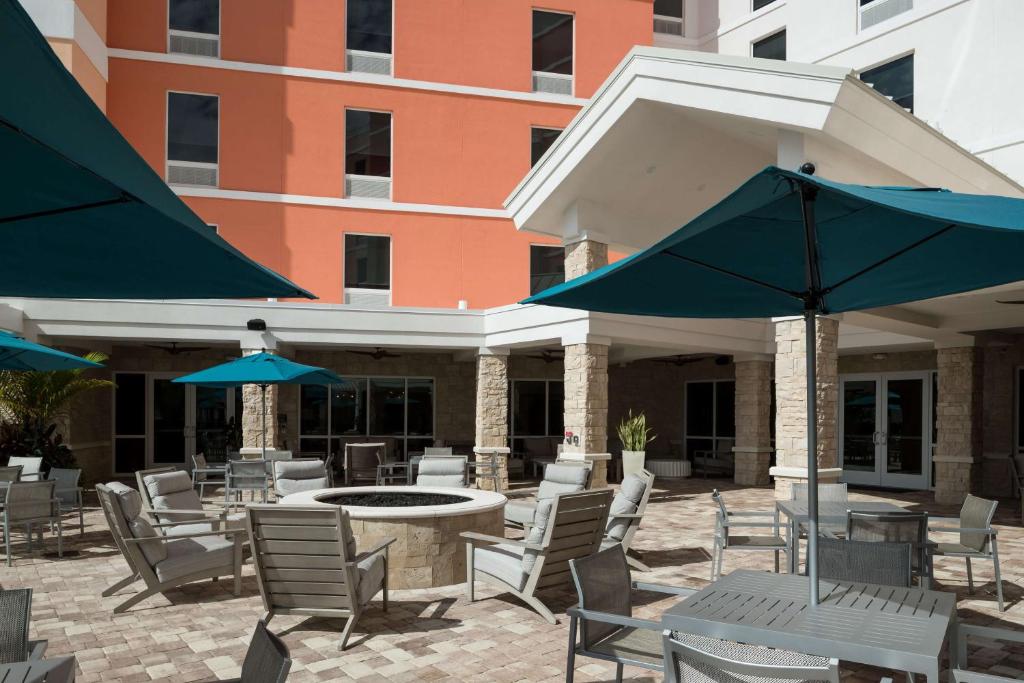 an outdoor patio with tables and chairs and umbrellas at Hampton Inn & Suites Cape Canaveral Cruise Port, Fl in Cape Canaveral