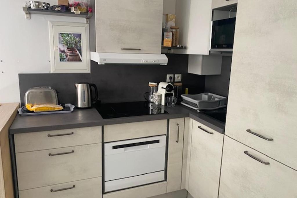 a kitchen with white cabinets and a black counter top at Apartment cosy with terrace 200m from the sandy beaches wifi in Juan-les-Pins