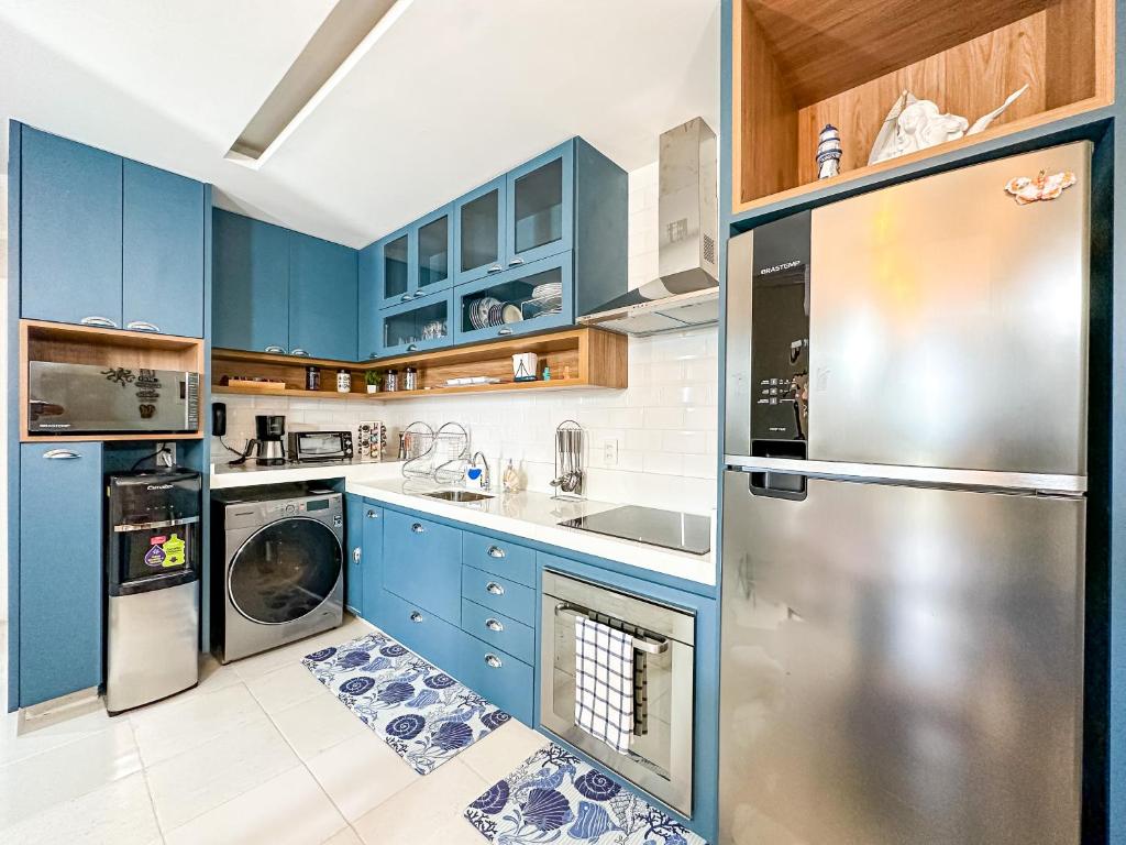 a kitchen with blue cabinets and a stainless steel refrigerator at Beach Living - pé na areia, 200m do Beach Park in Aquiraz
