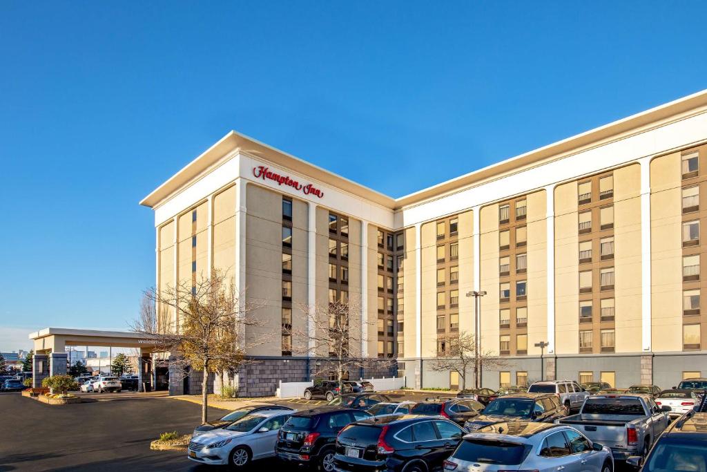 un gran edificio con coches estacionados en un estacionamiento en Hampton Inn Boston Logan Airport en Boston