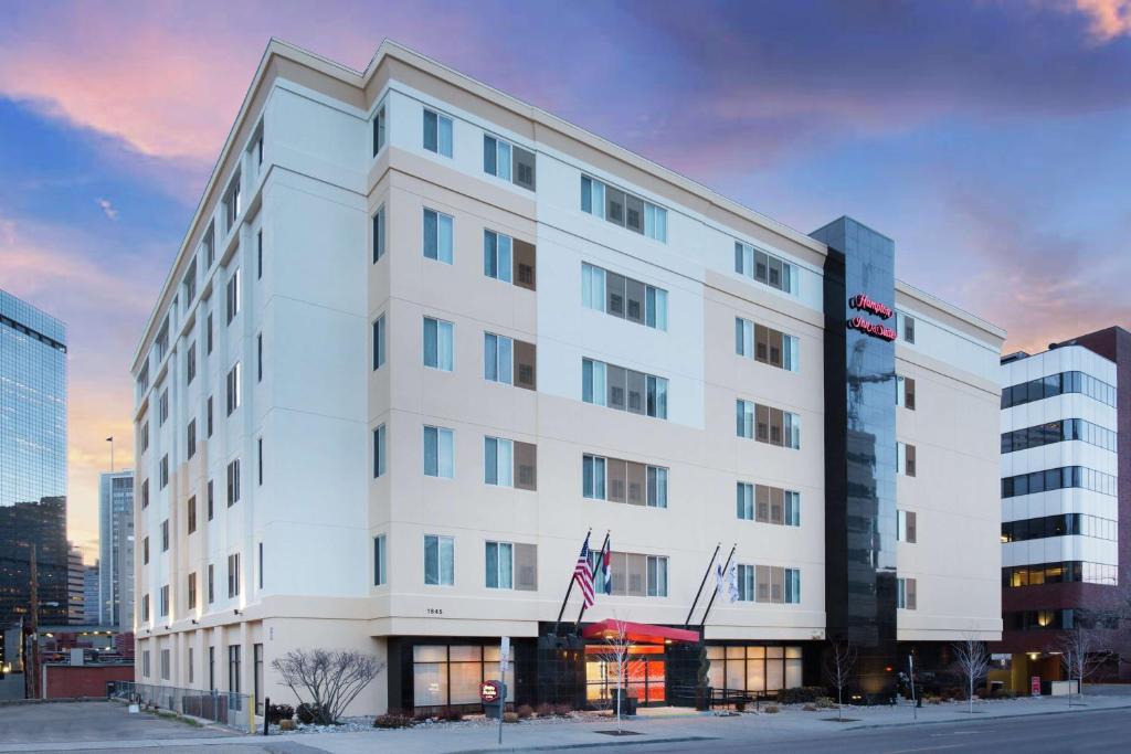 Hampton Inn & Suites Denver-Downtown في دنفر: مبنى أبيض مع علم أمريكي أمامه