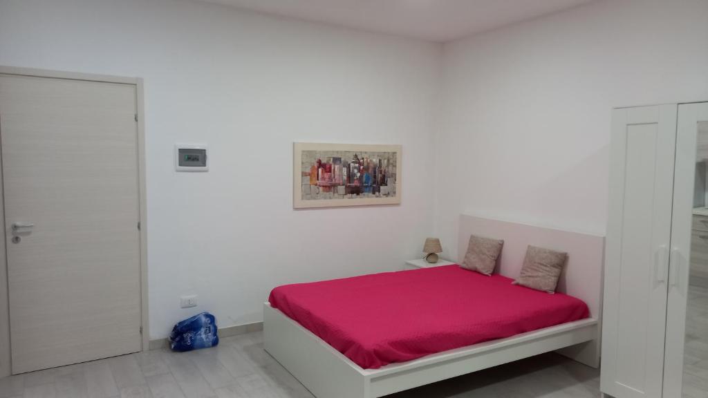 1 dormitorio blanco con 1 cama con sábanas rosas en casa vacanza San Francesco di paola en Caltagirone