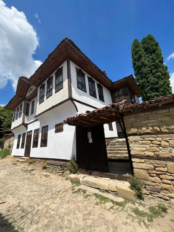 uma grande casa branca com um edifício de pedra em Къща за гости Никула Чорбаджи em Zheravna